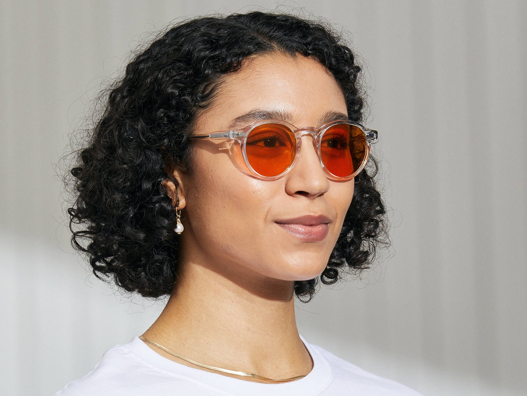 Model is wearing The MILTZEN in Crystal in size 49 with Woodstock Orange Tinted Lenses Model is wearing The MILTZEN in Crystal in size 49 with Woodstock Orange Tinted Lenses