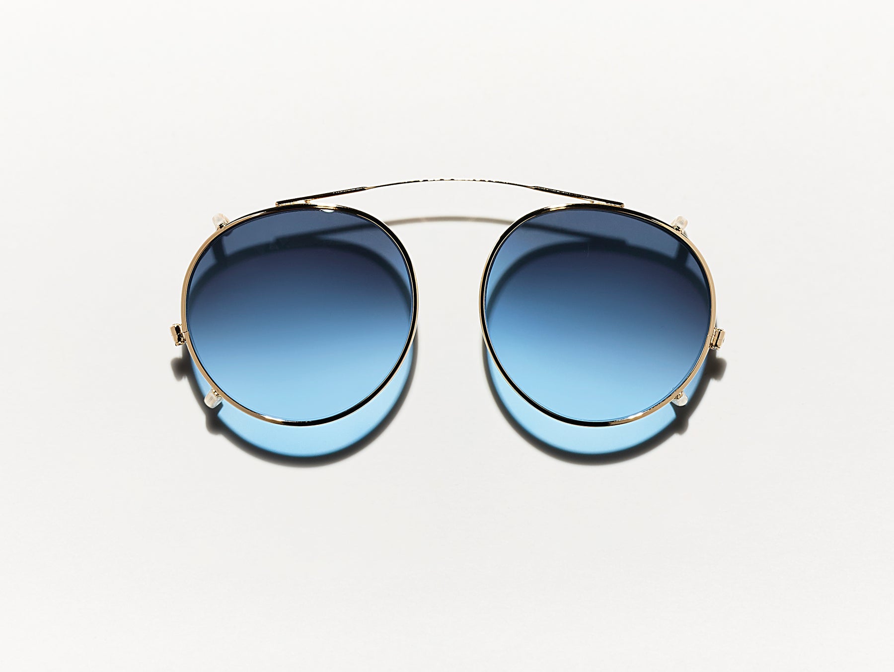 The CLIPZEN in Gold with Denim Blue Tinted Lenses The CLIPZEN in Gold with Denim Blue Tinted Lenses
