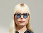 Model is wearing The DOLT CLIP in Gold in size 46 with Celebrity Blue Tinted Lenses