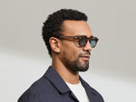 Model is wearing The DOLT SUN in size 46 in Cognac with Mineral Blue Tinted Lenses