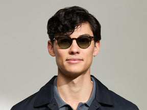 Model is wearing The FEVEL SUN in Dark Green in size 49 with Forest Wood Tinted Lenses