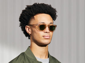 Model is wearing the FRITZ SUN in Cinnamon/Flesh in size 44 with Calibar Green Glass Lenses