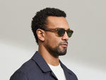 Model is wearing The LEMTOSH SUN in size 46 in Cognac with Calibar Green Tinted Lenses