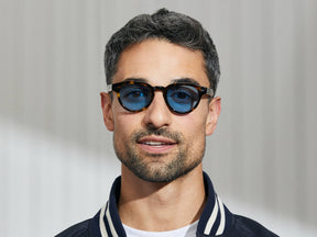 Model is wearing The MAYDELA SUN in Classic Havana in size 46 with Celebrity Blue Tinted Lenses