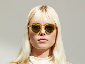 Model is wearing The MILTZEN SUN W/ METAL NOSE PADS in Blonde in size 46 with Calibar Green Glass Lenses