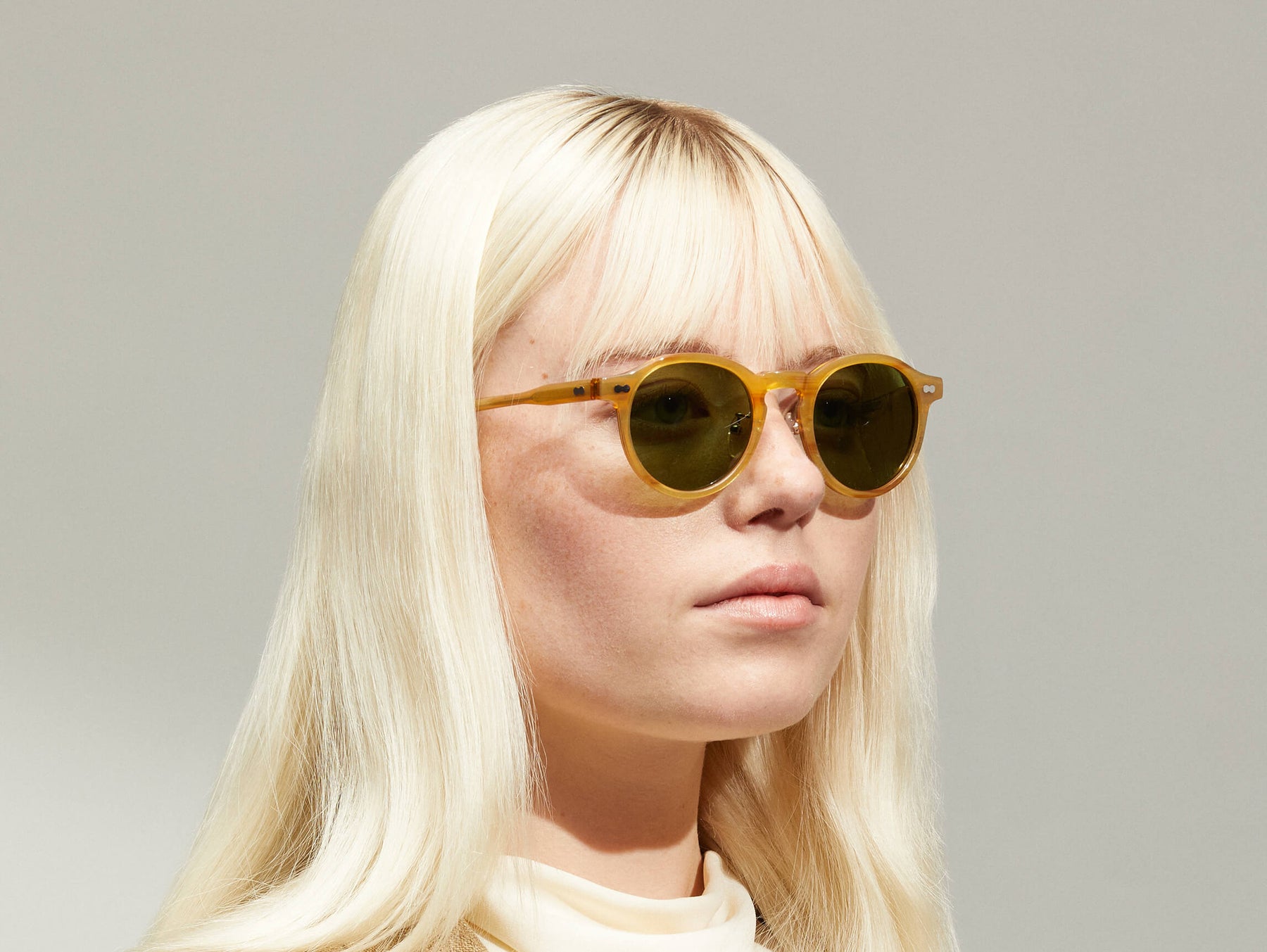 Model is wearing The MILTZEN SUN W/ METAL NOSE PADS in Blonde in size 46 with Calibar Green Glass Lenses