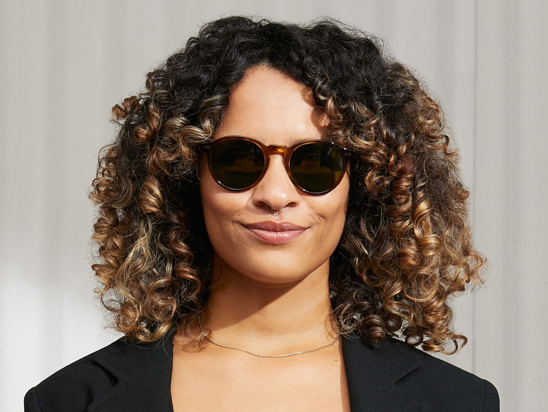 Model is wearing The MILTZEN SUN in Tobacco in size 49 with Calibar Green Lenses