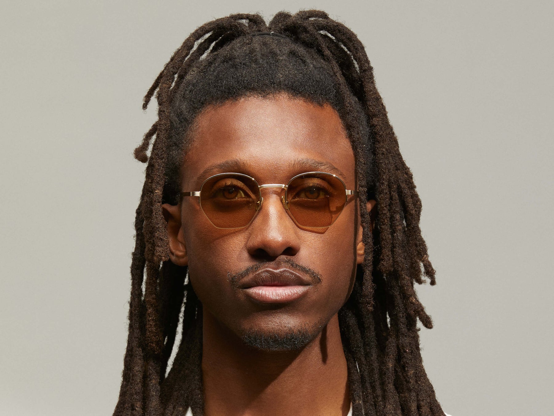 Model is wearing The PLOTZ SUN in size 49 in Gold with Amber Tinted Lenses