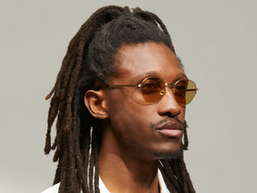 Model is wearing The PLOTZ SUN in size 49 in Gold with Amber Tinted Lenses