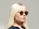 Model is wearing The PLOTZ SUN in size 49 in Gold with G-15 Tinted Lenses