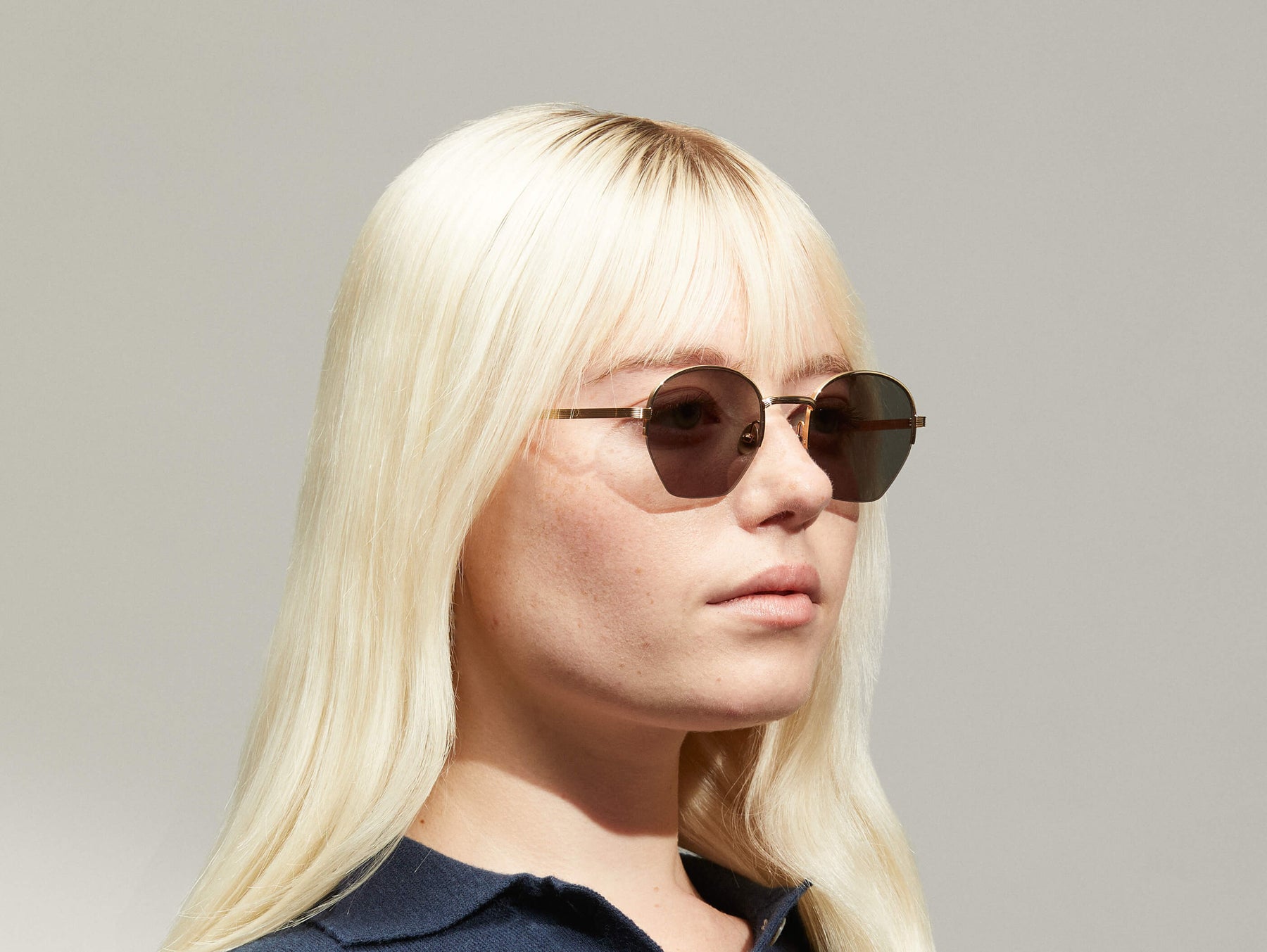 Model is wearing The PLOTZ SUN in size 49 in Gold with G-15 Tinted Lenses