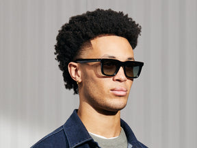 Model is wearing The RIZIK in Black in size 49 with Forest Wood Tinted Lenses