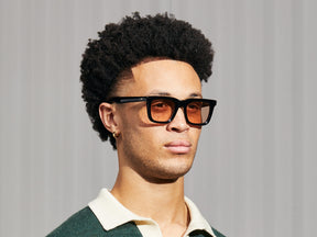 Model is wearing The RIZIK in Black in size 49 with New York Rose Tinted Lenses