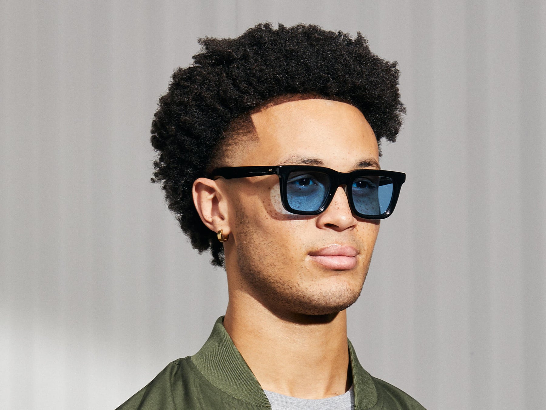 Model is wearing The RIZIK in Black in size 49 with Celebrity Blue Tinted Lenses