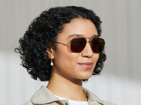 Model is wearing The SHTARKER SUN in Gold in size 57 with Cosmitan Brown Lenses