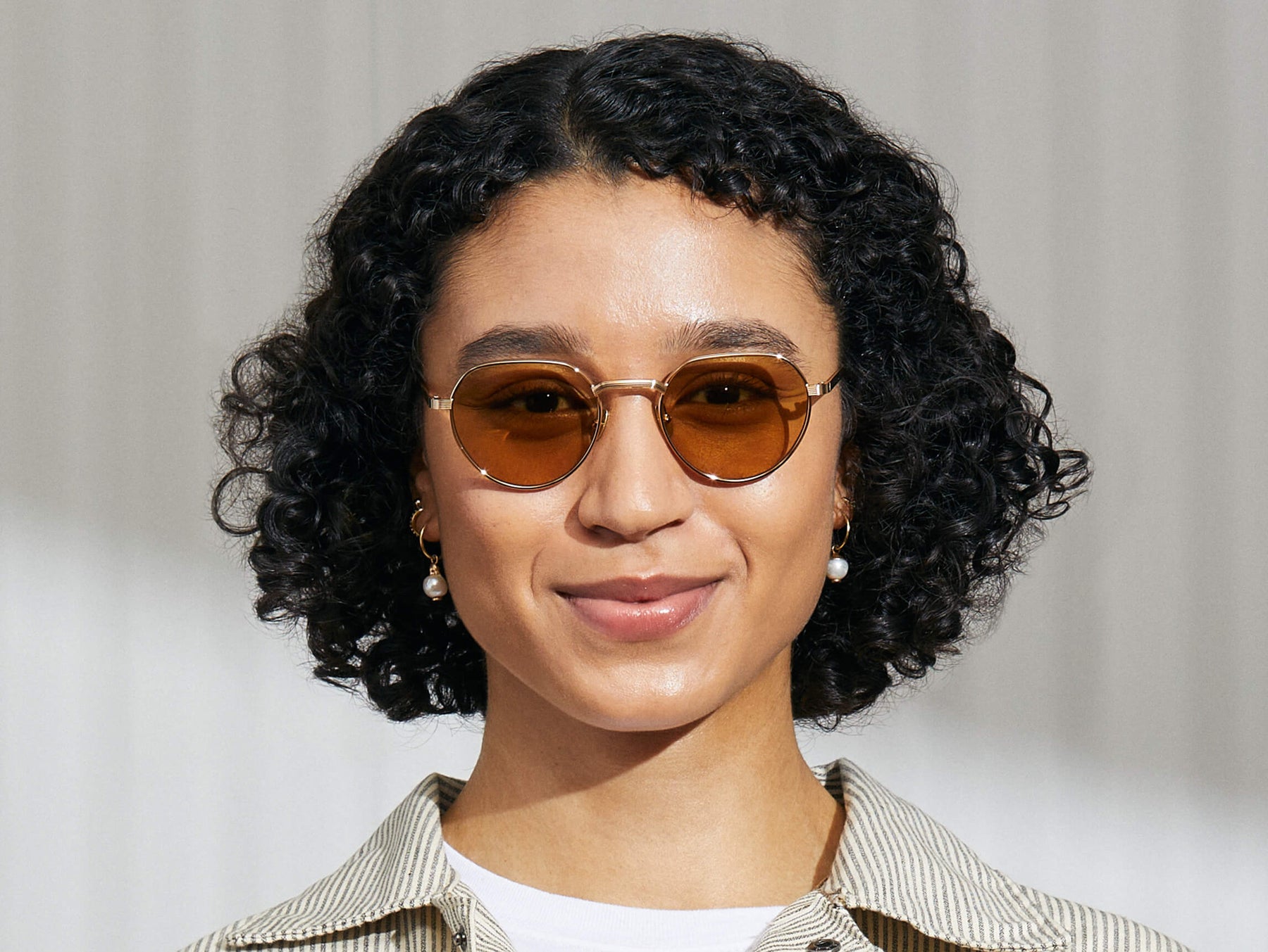 Model is wearing The SMENDRIK SUN in Gold in size 51 with Amber Tinted Lenses