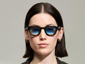 Model is wearing The TELENA  in Tortoise/Black in size 44 with Broadway Blue Tinted Lenses