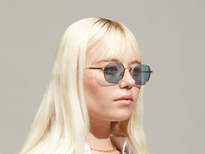 Model is wearing The UTZ SUN in size 50 in Gold with Blue Tinted Lenses
