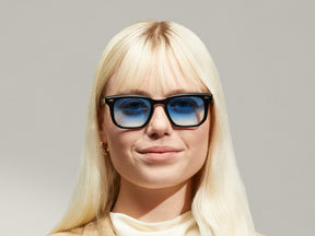 Model is wearing The ZISSEL SUN in size 49 in Black with Broadway Blue Tinted Lenses