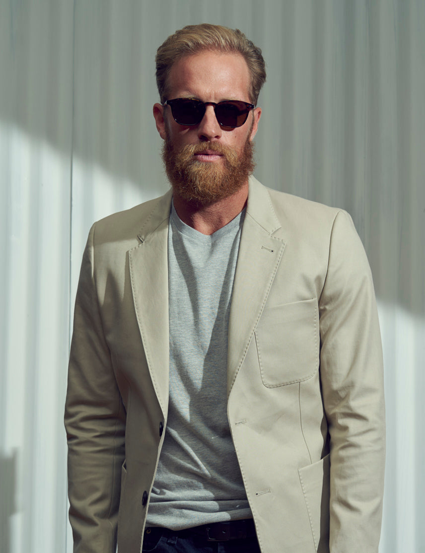 Model is wearing The GENUG SUN in Spot Tortoise/Gold in size 50 with Cosmitan Brown Glass Lenses