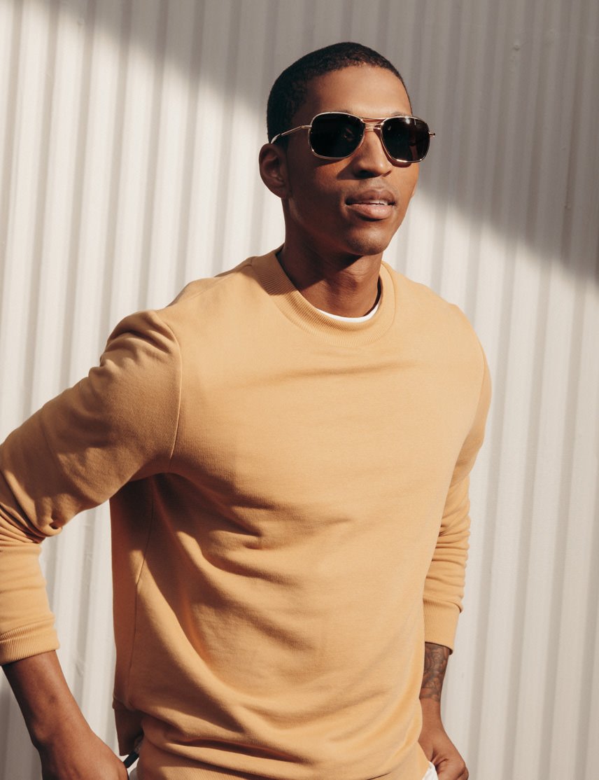 Model is wearing The HELDISH SUN in Gold in size 57 with Cosmitan Brown Glass Lenses