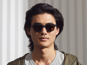 Model is wearing The MORRIS SUN in Matte Black in size 50 with Cosmitan Brown Glass Lenses