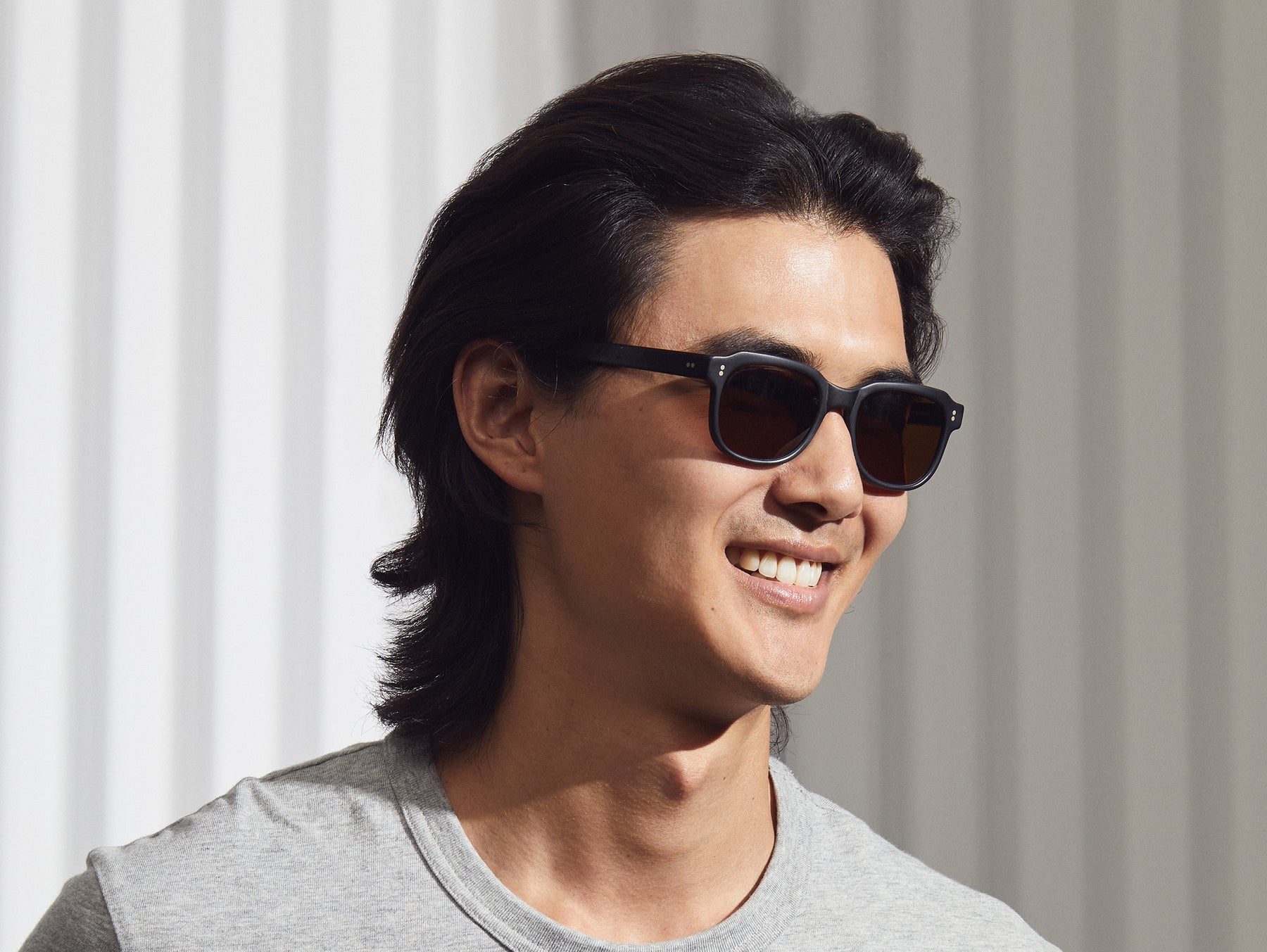 Model is wearing The MORRIS SUN in Matte Black in size 50 with Cosmitan Brown Glass Lenses