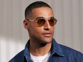 Model is wearing The SMENDRIK SUN in Gold in size 48 with Amber Tinted Lenses